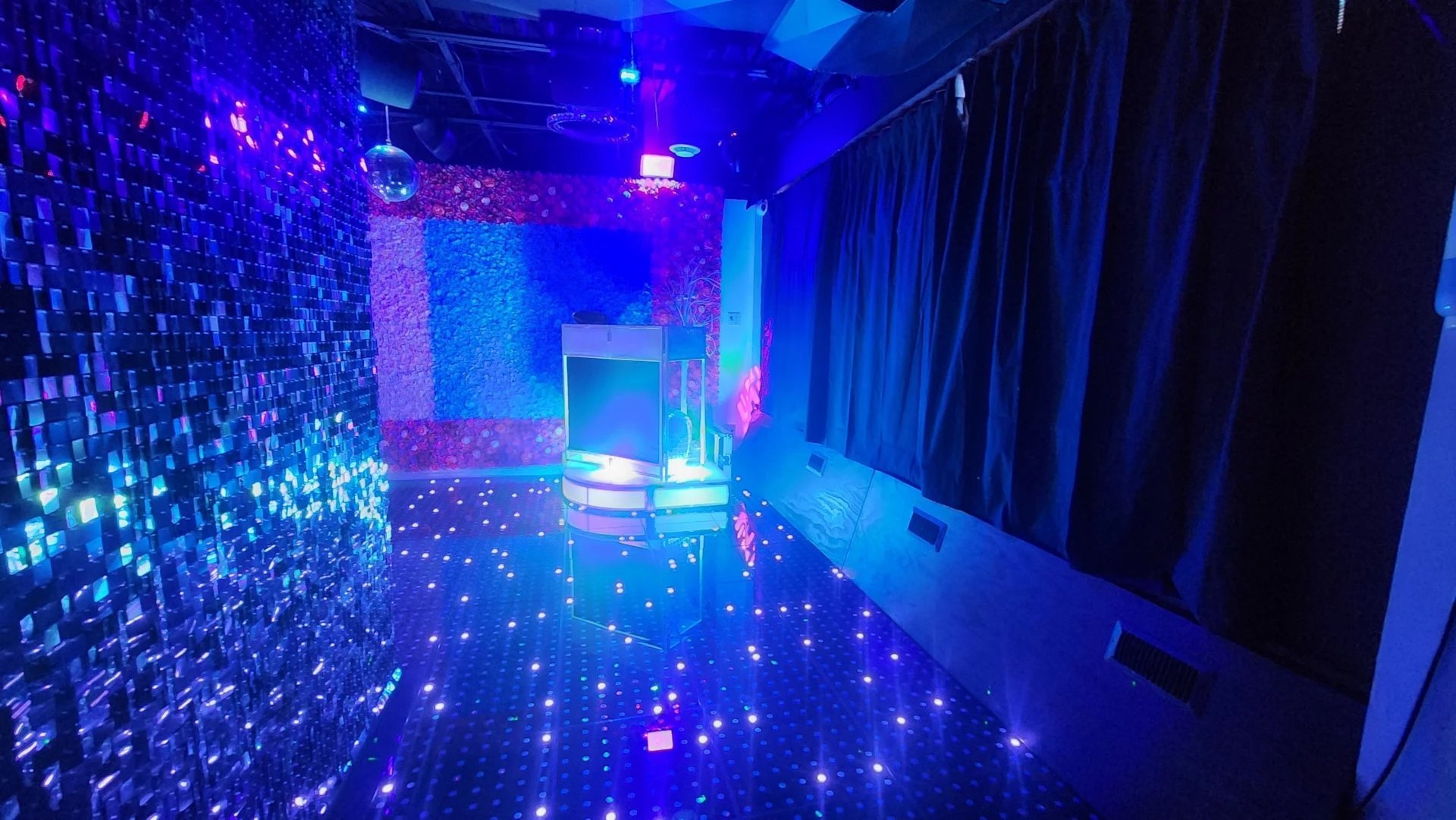 Futuristic neon-lit digital room with glowing blue and pink lights, LED floor panels, and illuminated walls creating an immersive tech environment