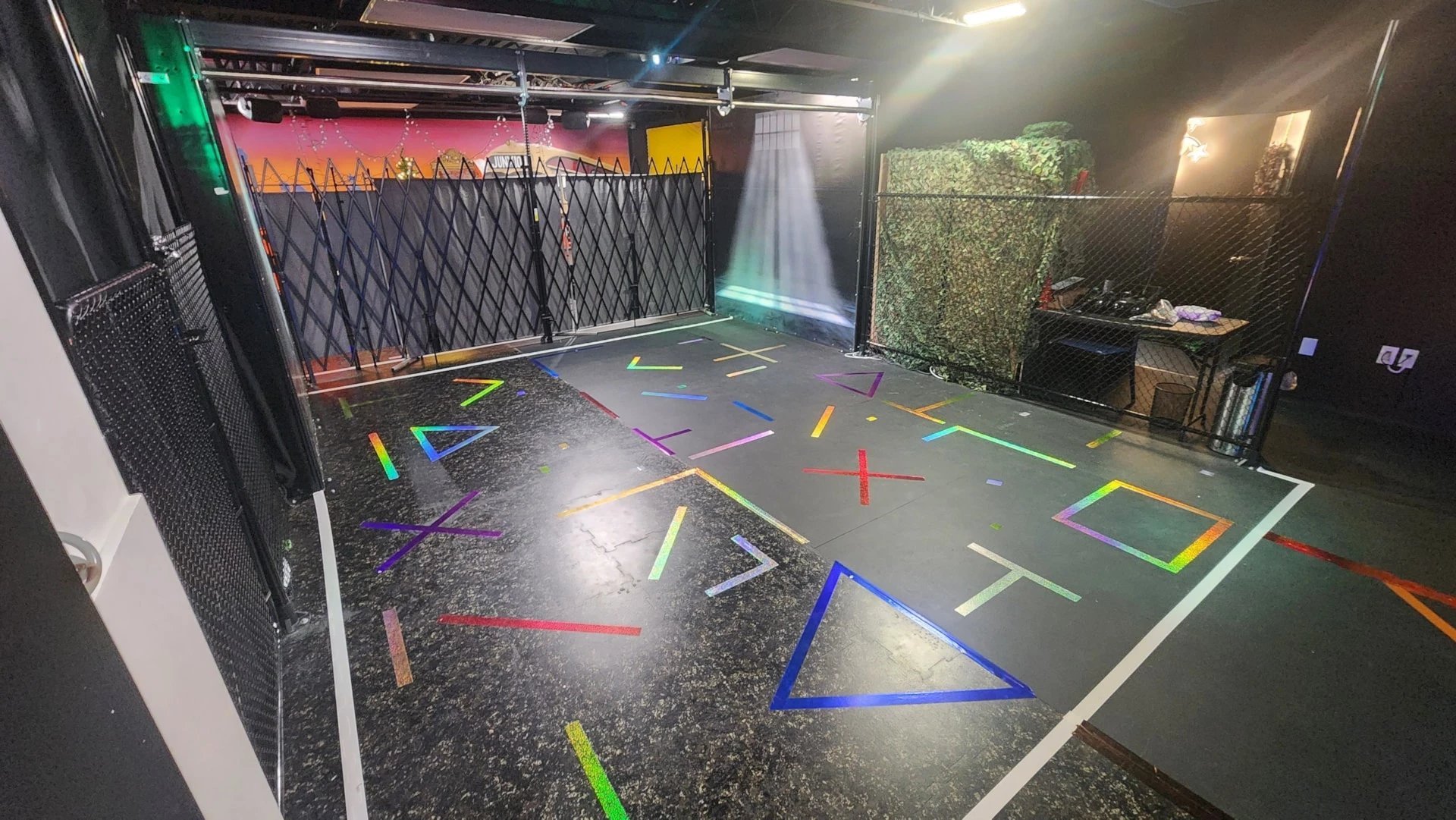 Indoor gym space with colorful geometric shapes and lines marked on dark floor for fitness training exercises