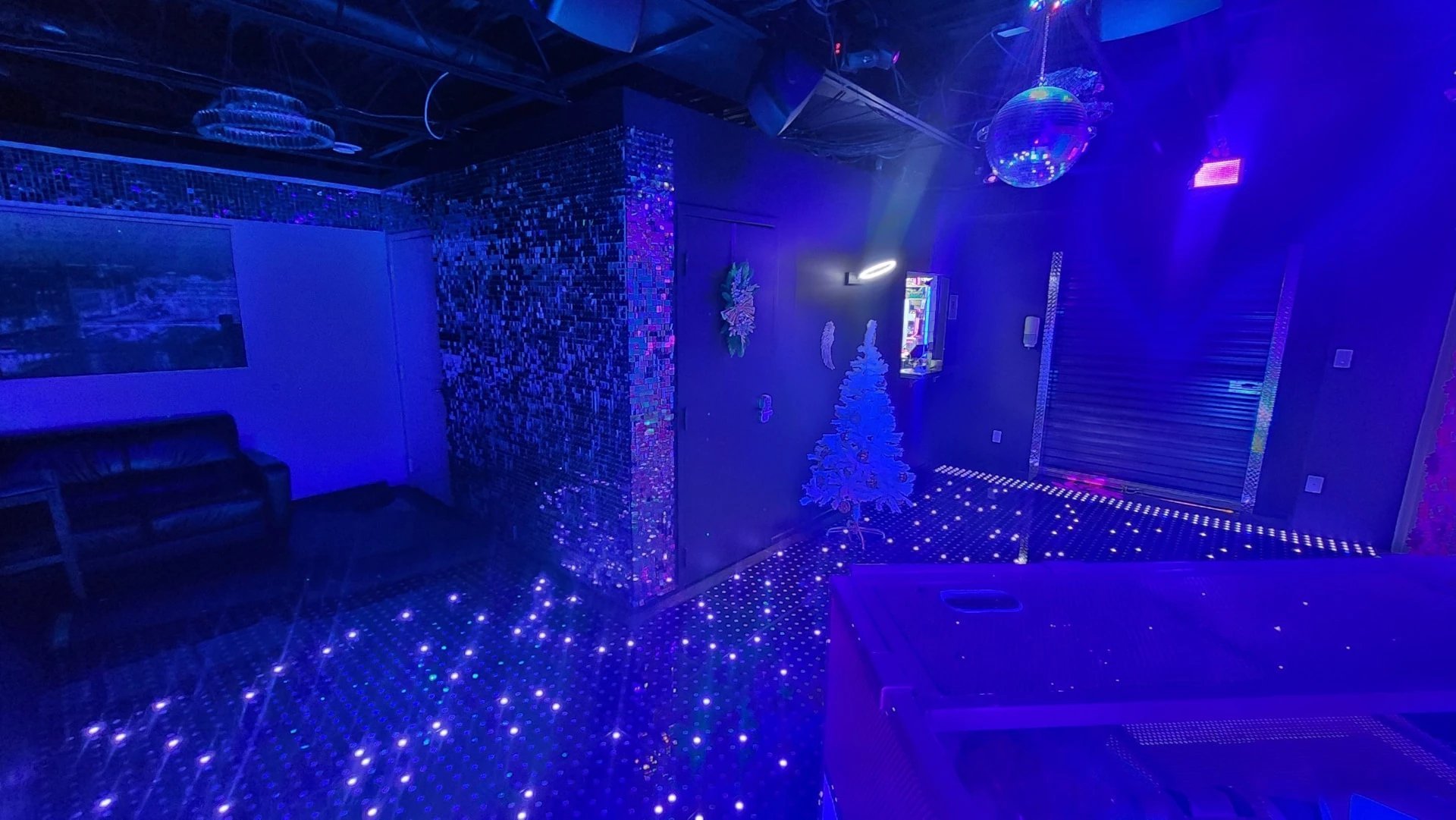 Modern nightclub interior with purple neon lighting, LED floor, and illuminated walls creating a vibrant dance venue atmosphere