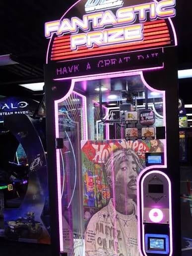 Neon-lit vintage arcade game cabinet labeled Fantastic Prize with purple and red signage, displaying Have a Great Day message