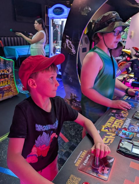 Children playing arcade games in a colorful gaming venue with neon lighting and illuminated cabinet displays